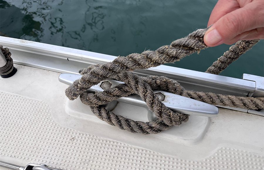 Tripulante del Mare Nostrum ejecutando la vuelta mordida —
     paso final del método clásico de afirmado O → X → llave —
     en la cornamusa de cubierta de estribor. CNDN, Recreo.