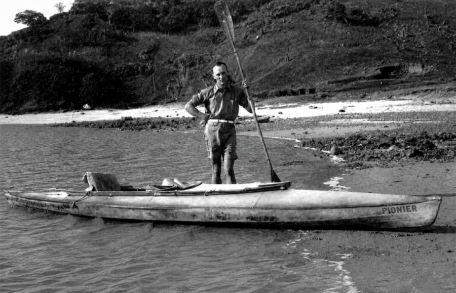 Oskar Speck de pie junto a su kayak de la marca Pionier en una playa