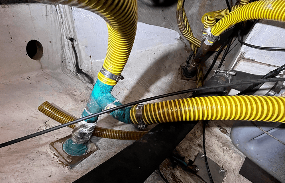 Confluencia de los ramales de los imbornales bajo la bañera del Lancet. Las mangueras de proa y popa se reúnen en las descargas comunes que continúan hacia las válvulas de fondo.